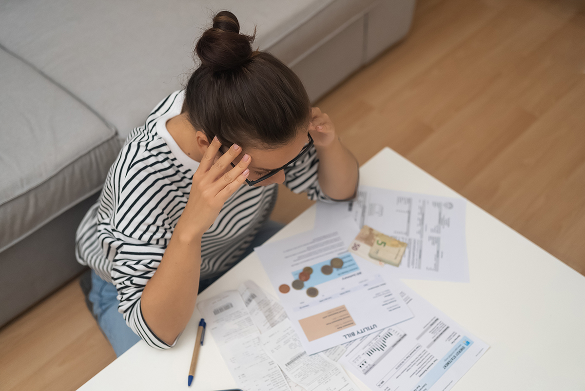 Person stressed over bills and coins at a table.