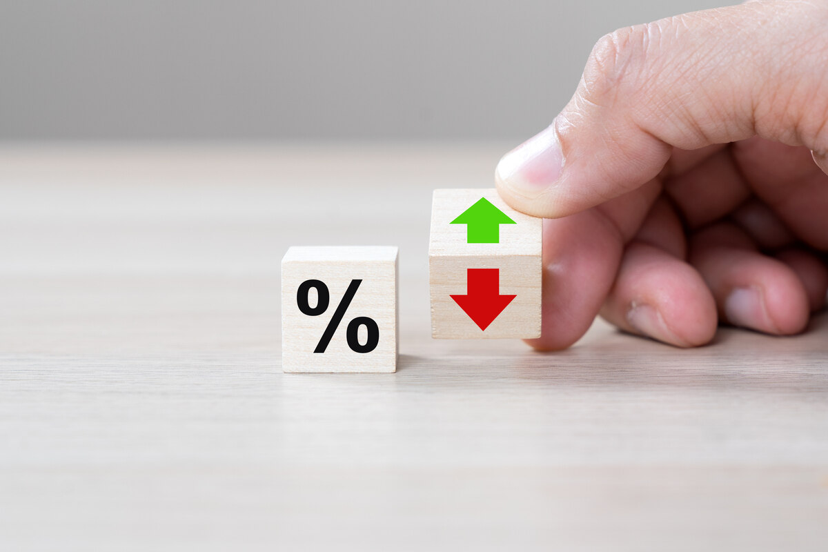 percent sign for adjustable-rate mortgage and fingers of a hand holding a dice with an up and down arrow